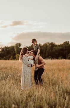 a family is standing in the middle of a field with their son on his shoulders