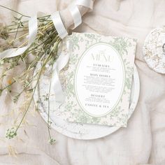 a table setting with napkins and flowers on the plate, next to some ribbons