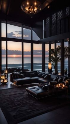 a living room filled with lots of furniture and large windows overlooking the ocean at night