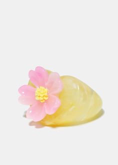 a pink flower sitting on top of a yellow object