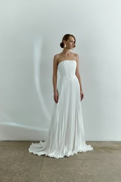 a woman in a white dress is standing on the concrete floor with her hands behind her back