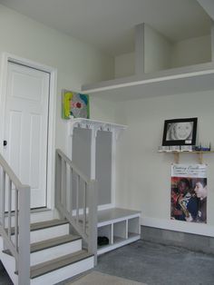 there is a white door and stairs in this house with pictures on the wall above it