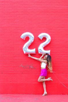 a young woman is posing in front of a red wall with the letter s2 painted on it