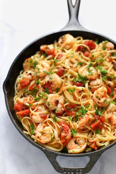 pasta with shrimp and tomatoes in a skillet on a marble countertop, ready to be eaten