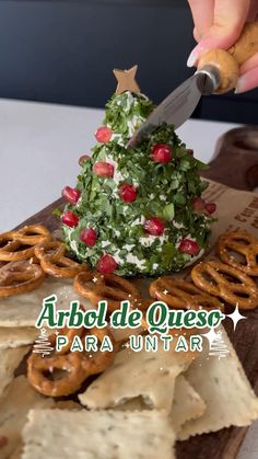 a person cutting into a christmas tree made out of pretzels and other food