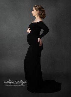 a pregnant woman in a black gown poses for the camera with her hands on her hips