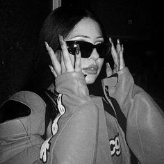 a woman wearing sunglasses and holding her hands up to her face while talking on the phone