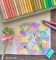 a drawing of a bunny holding a flower next to some colored pencils and crayons