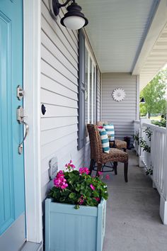 the front porch is decorated with blue and white accents, including a planter filled with pink flowers