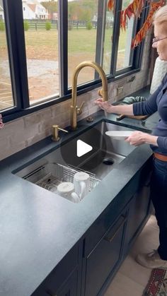 a woman standing in front of a kitchen sink next to a window with an open window