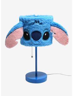 a blue and pink hat with ears is on top of a light that has a cord attached to it