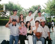 a group of people sitting on top of a basketball court with one man holding a basketball