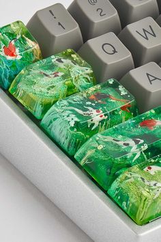 a close up of a computer keyboard with fish on the keys and green leaves painted on it