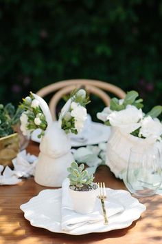 the table is set with white flowers and succulents