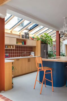 a kitchen with blue and orange stools next to an island in the middle of it