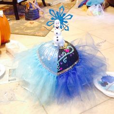 a frozen princess costume sitting on top of a blue tulle skirt with a snowman figure