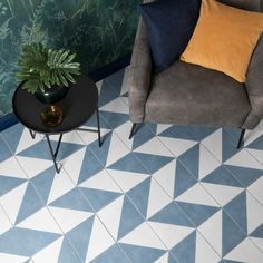 a living room with blue and white flooring next to a gray chair, black table and plant