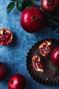 some pomegranates are sitting on a plate next to two pieces of fruit