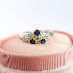 a diamond and sapphire ring sitting on top of a pink box