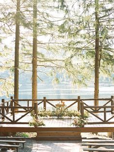 an outdoor ceremony setup with benches and flowers on the table in front of some trees