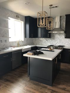 a large kitchen with black cabinets and white counter tops, an island in the middle