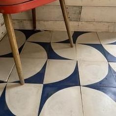 a red chair sitting on top of a blue and white floor next to a wooden bench