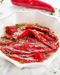 a white bowl filled with red sauce next to a chili pepper