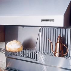 a loaf of bread sitting on top of a metal shelf next to a coffee pot