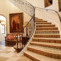 a staircase leading up to a living room with paintings on the wall and tiled flooring