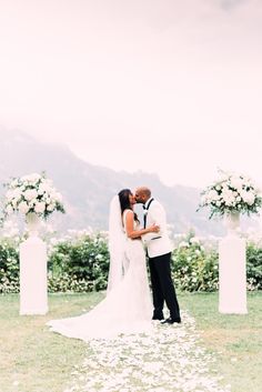 a bride and groom kissing in front of their wedding ceremony archs with white flowers