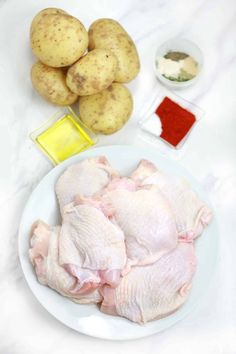 raw chicken and potatoes on a white plate