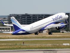 a large jetliner taking off from an airport tarmac with buildings in the background