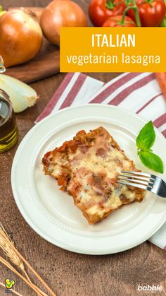 a white plate topped with lasagna on top of a table next to vegetables