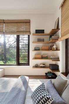 a bed sitting in a bedroom next to a window with wooden shelves on the wall