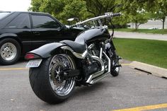 a black motorcycle parked in a parking lot next to a car