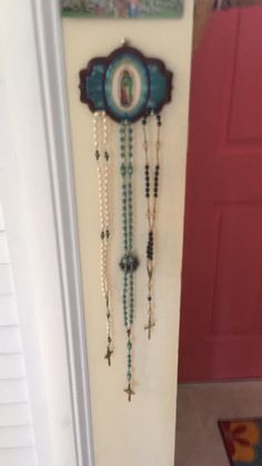 a clock with beads hanging on the wall next to a red door in a house