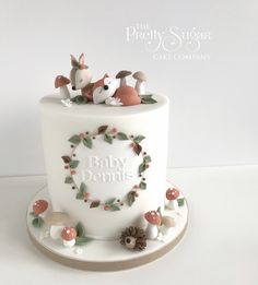 a white cake decorated with woodland animals and leaves