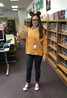 a woman standing in front of a bookshelf holding up a book with ears