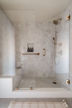 a walk in shower sitting next to a bath tub with a white rug on the floor