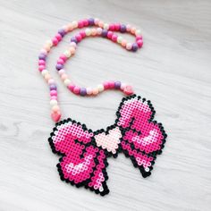 a pink and black bow necklace on a white wooden table next to a pair of scissors