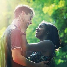 a man and woman standing next to each other with trees in the back ground behind them