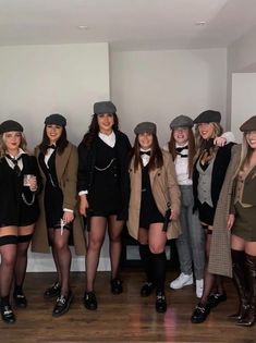 a group of young women dressed in vintage clothing and hats posing for a photo together