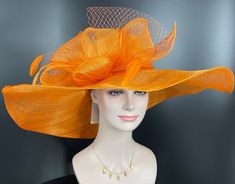 "The oversized brim adorned with a jumbo sinamay bow in and feathers  design characterizes this horse racing event hat made of natural straw. The large brim creates a statement piece, and the sinamay jumbo bow  and netting adds a touch of whimsy and feminine elegance. Crafted from straw, it exudes a light and airy feel, making it a stylish and comfortable choice for a day at the races. The hat combines the classic appeal of a wide brim with the playful charm of a jumbo sinamay bow and netting , Orange Costume Hat For Kentucky Derby Races, Orange Mini Hat For Kentucky Derby, Orange Hat For Kentucky Derby Races, Orange Hat For Kentucky Derby, Orange Formal Hat For Kentucky Derby, Elegant Orange Brimmed Hat, Orange Wide Brim Fascinator For Kentucky Derby, Royal Ascot Fedora Costume Hats And Headpieces, Sinamay Costume Hats For Royal Ascot Races