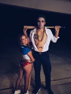 a man and woman dressed in costumes posing for the camera with a baseball bat on their shoulders