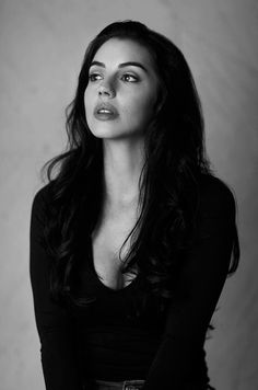 a black and white photo of a woman with long dark hair wearing a black shirt