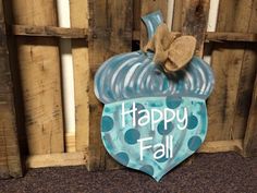 a happy fall sign hanging on the side of a wooden fence in front of some wood pallets