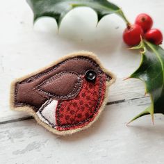 a red bird sitting on top of a wooden table next to holly leaves and berries