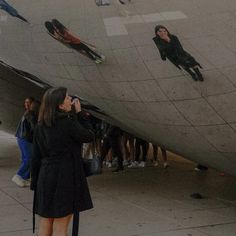 a woman is looking at the reflection of people in a large mirror ball that's reflecting them