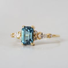 a blue and white diamond ring with two diamonds on it's sides, set in yellow gold