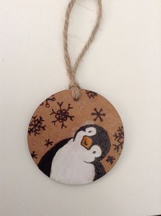 a wooden ornament with a penguin painted on it's face and snowflakes